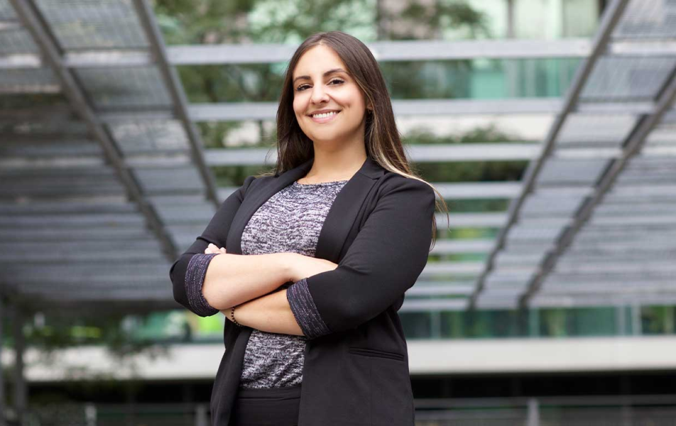 Woman in blazer standing with arms crossed and smiling