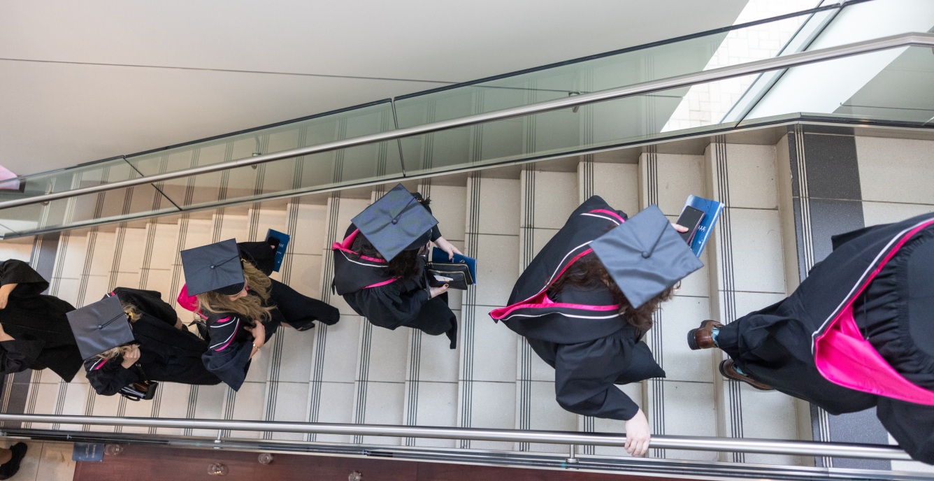 Graduates walking in a line up stairs