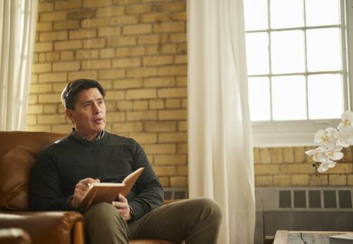 A man sitting in a counselling office writing in a notebook