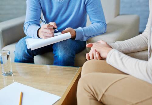 Two people with their faces out of screen, sitting together in a counselling office