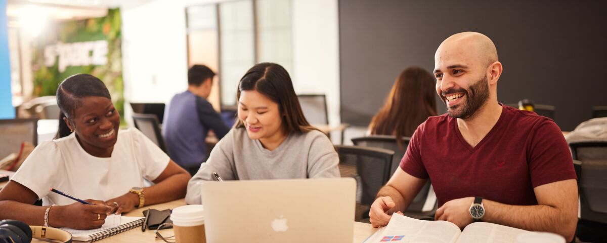 Three students sitting at desk with laptop