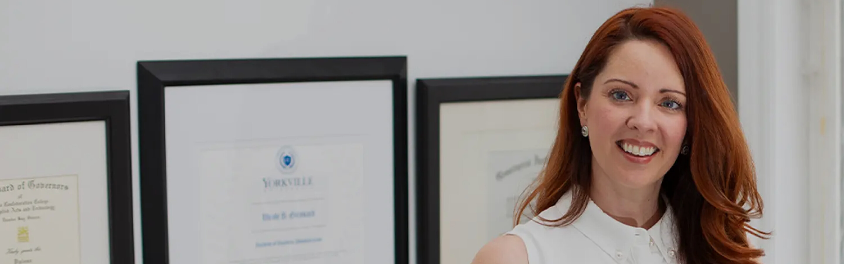 Woman standing in front of framed certificates