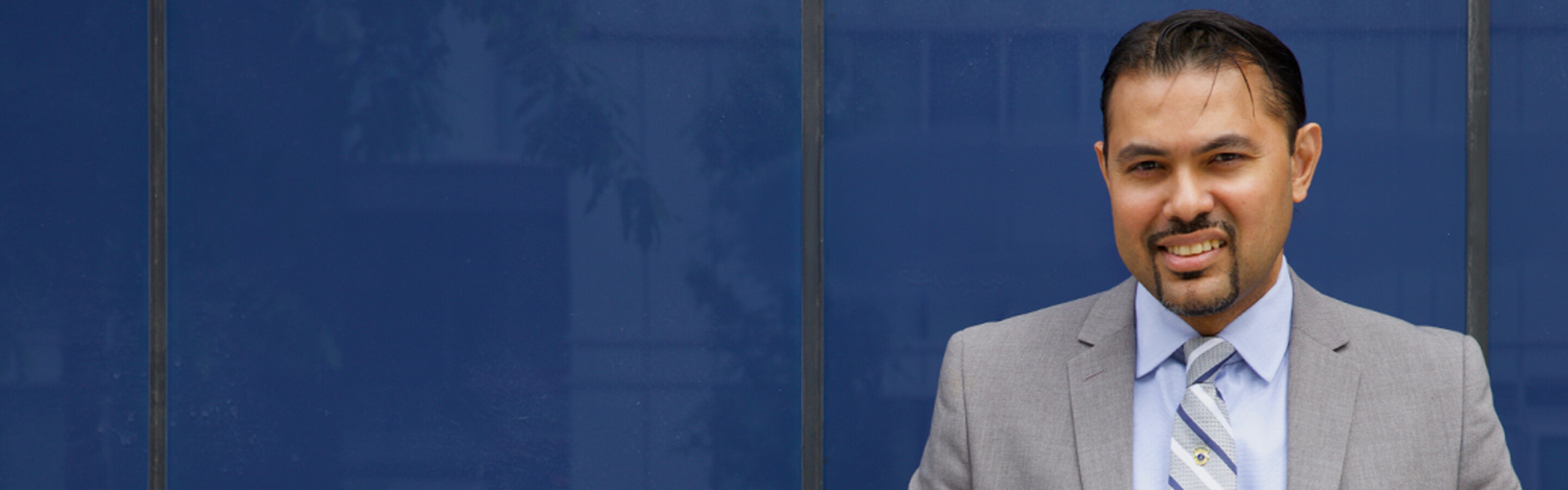 Man is suit standing in front of blue wall