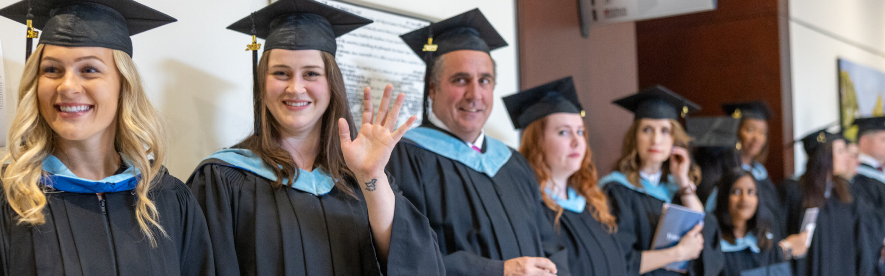 A long line of graduates standing together against a wall