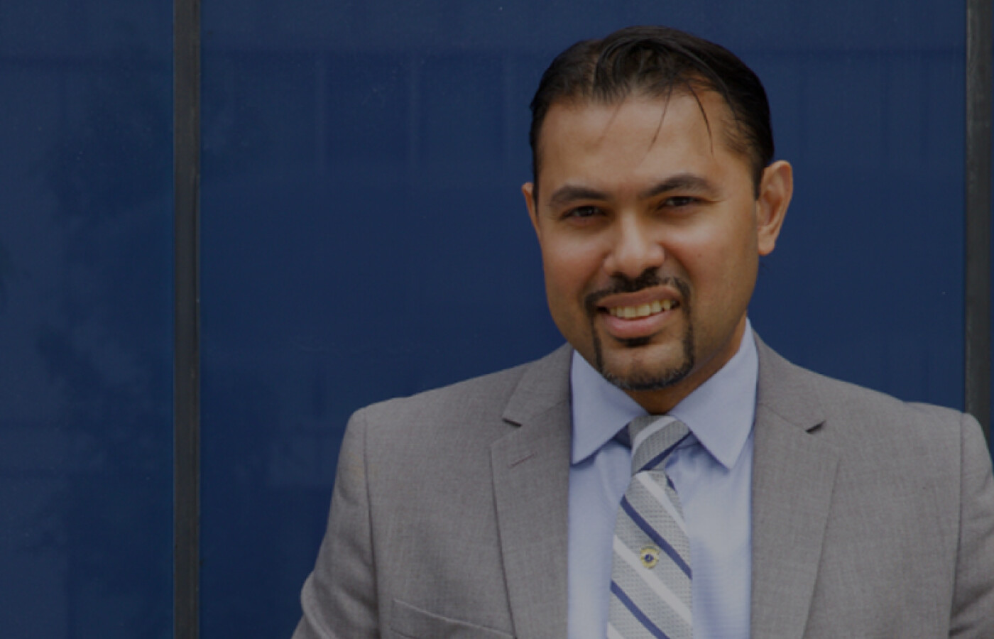 Man is suit standing in front of blue wall