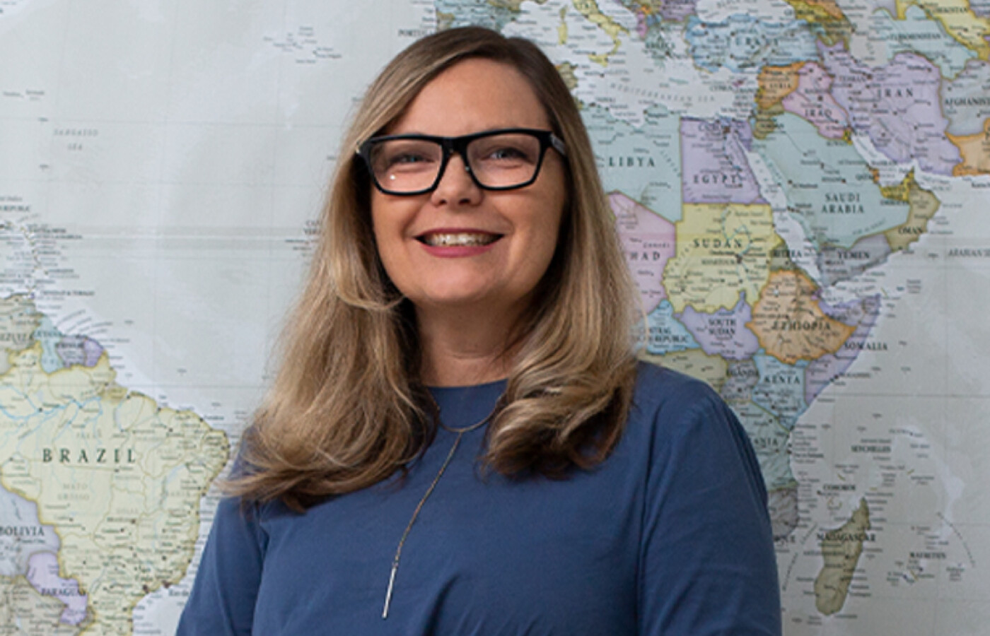 Woman with glasses standing in front of map