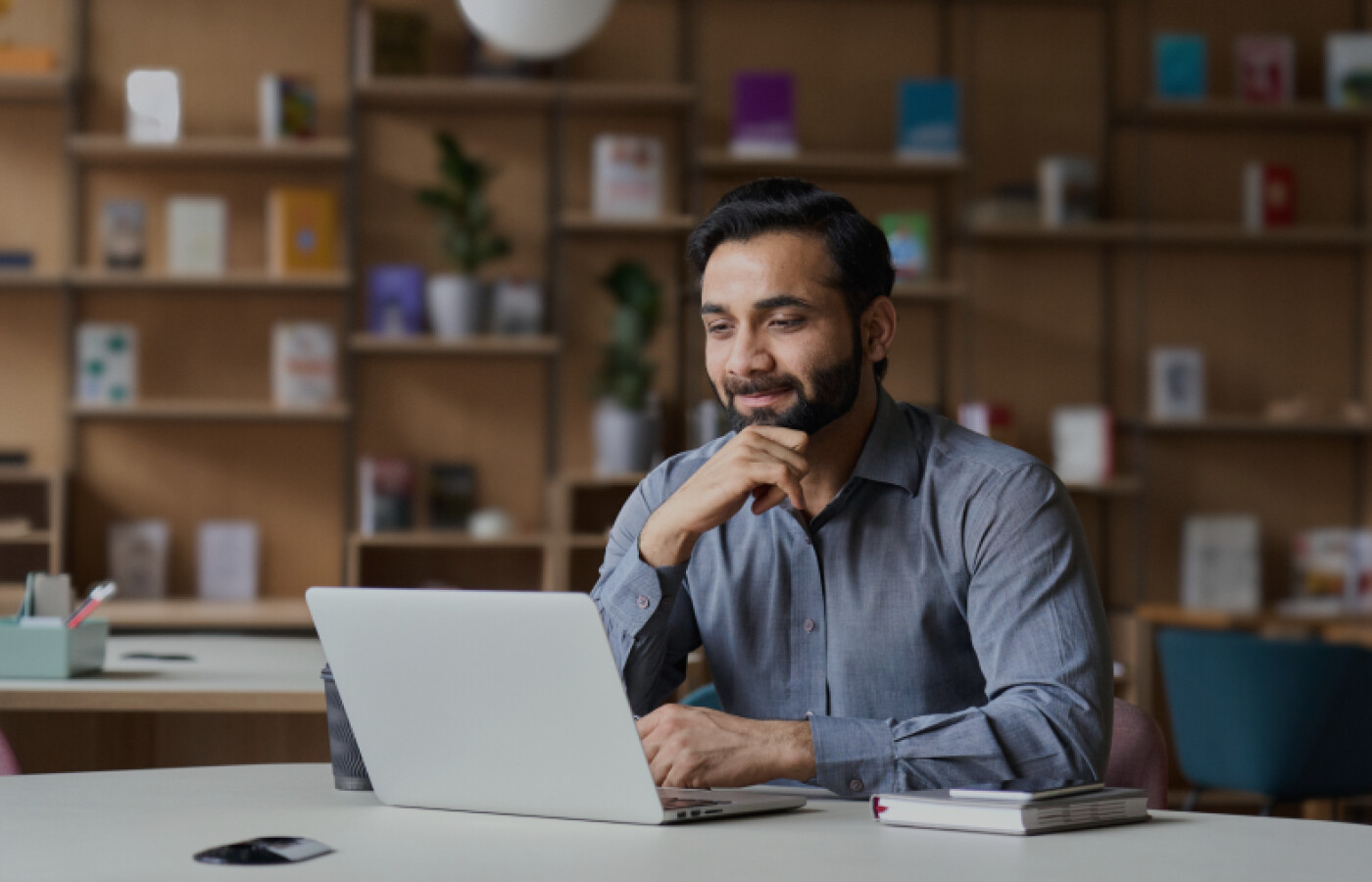 A man with a beard thinking while looking at a laptop